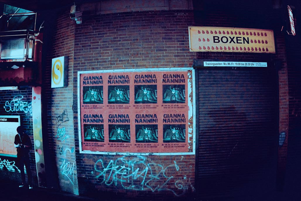 Kunstfoto einer blauen Neon-Graffiti-Wand mit Boxen-Schriftzug und 9 Fenstergittern, geheimnisvolles Licht.