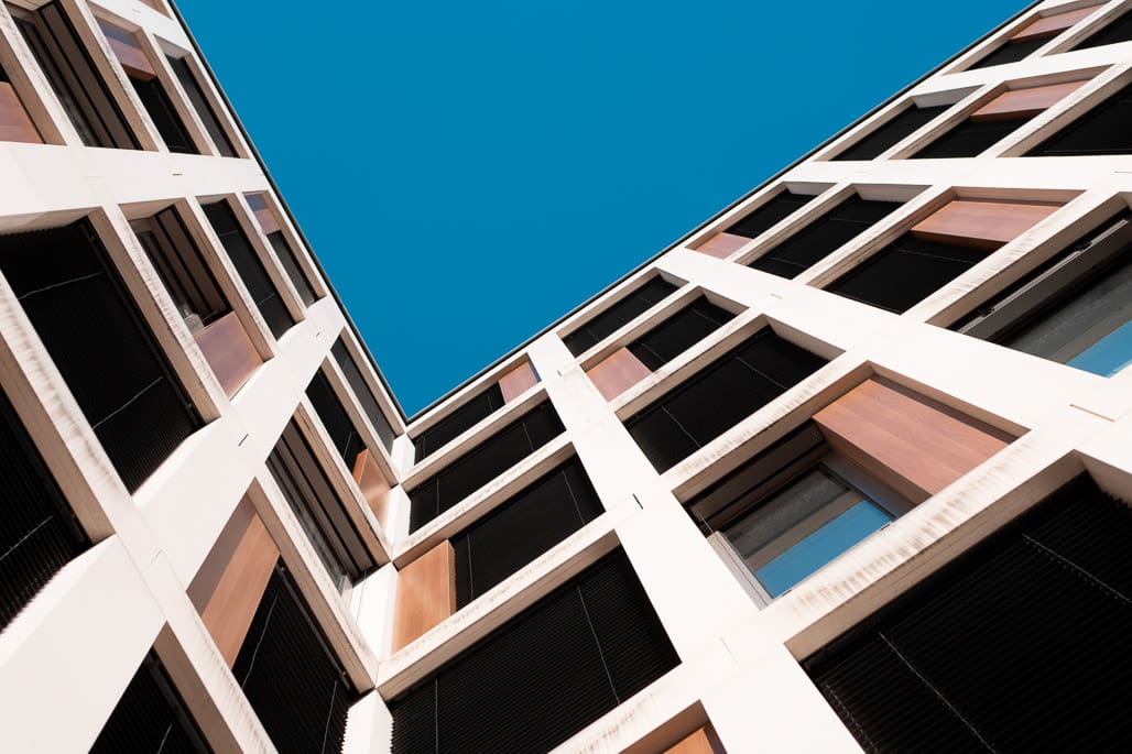 Kunstfotografie Köln betont geometrisches Eckgebäude vor strahlend blauem Himmel im Extremwinkel.