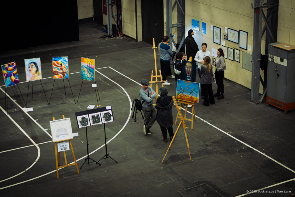 Weitwinkelaufnahme der Kalk Kunst 2025 in Köln-Kalk: Gemälde auf Staffeleien, Besucher:innen und Raumwirkung.