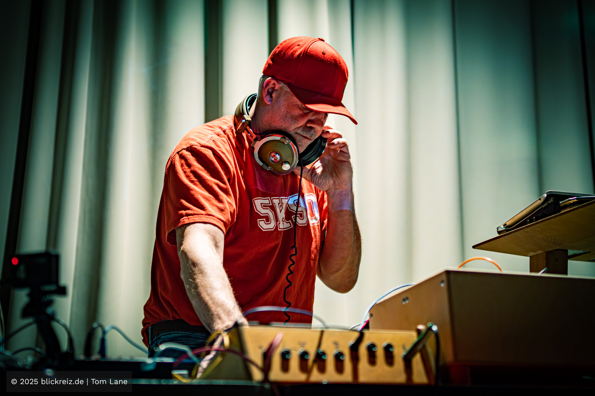 Endo Monk arbeitet vertieft an modularen Synths und Effektgeräten, während warmes Licht Kabel, Regler und Bewegung akzentuiert.